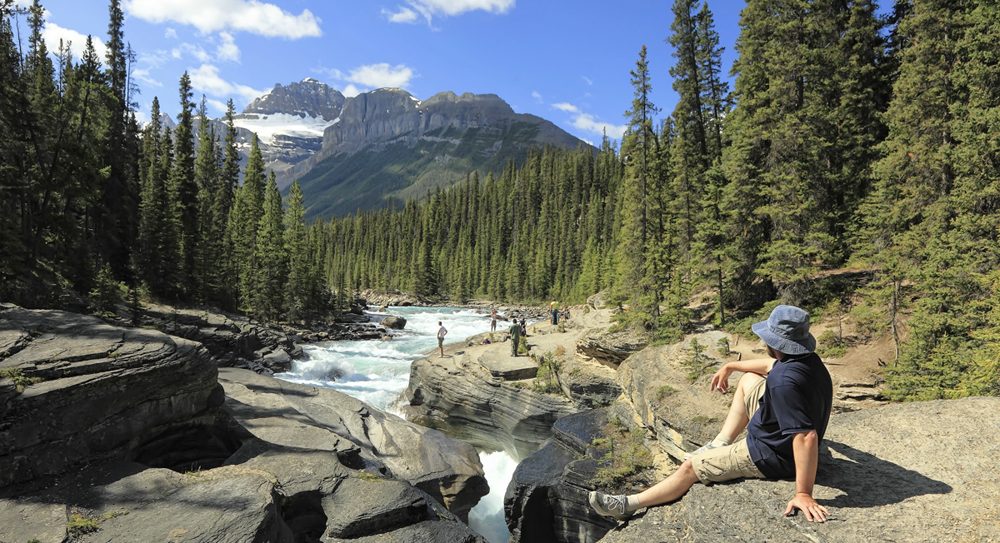 Backpacker sitzt an einem Fluss in Kanada
